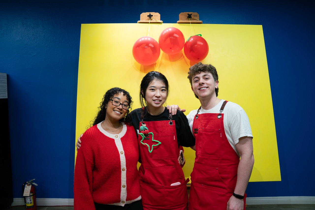 Three people posing in front of a colorful backdrop with balloons and a large star.