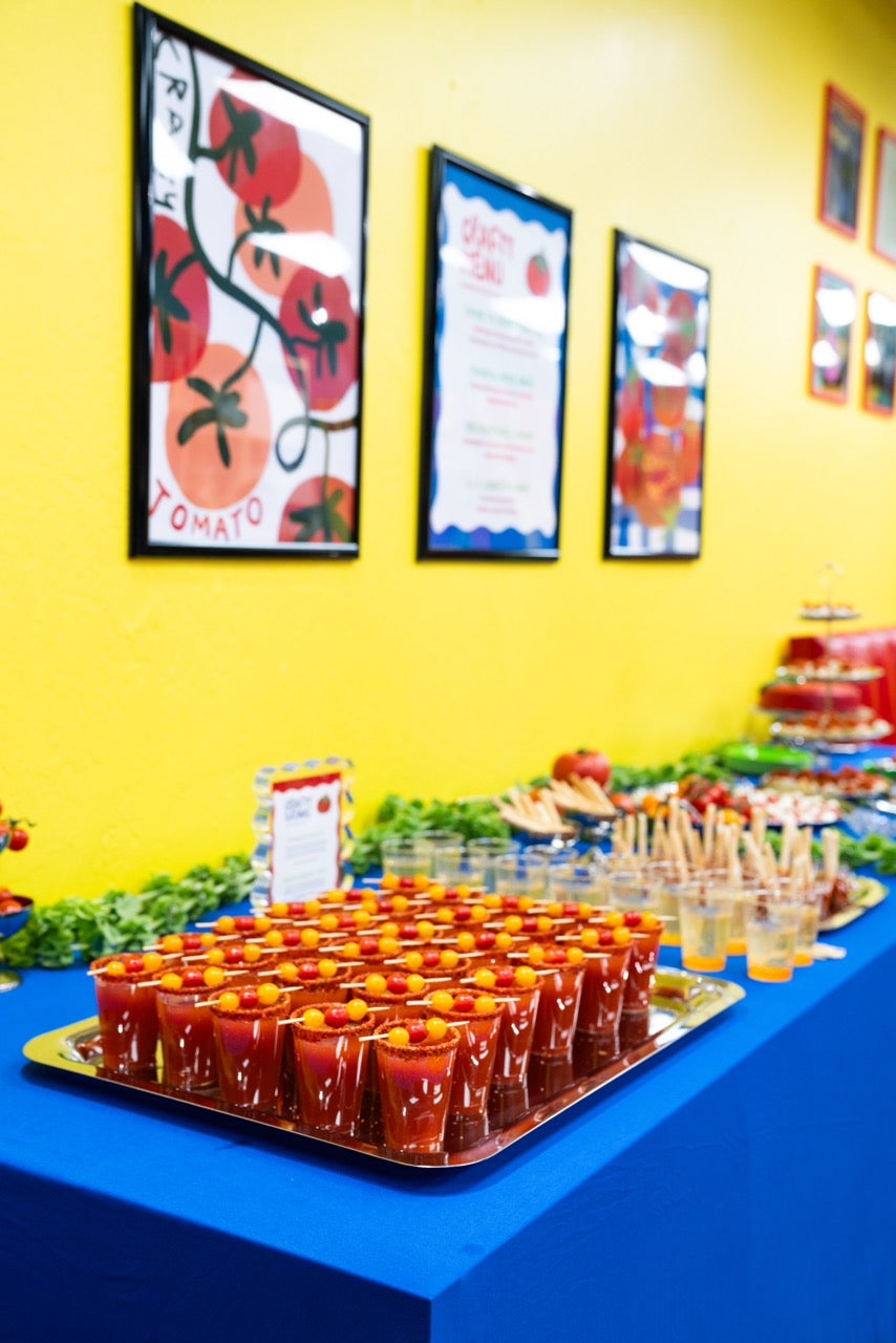 Table with food and drinks against a yellow wall with framed pictures
