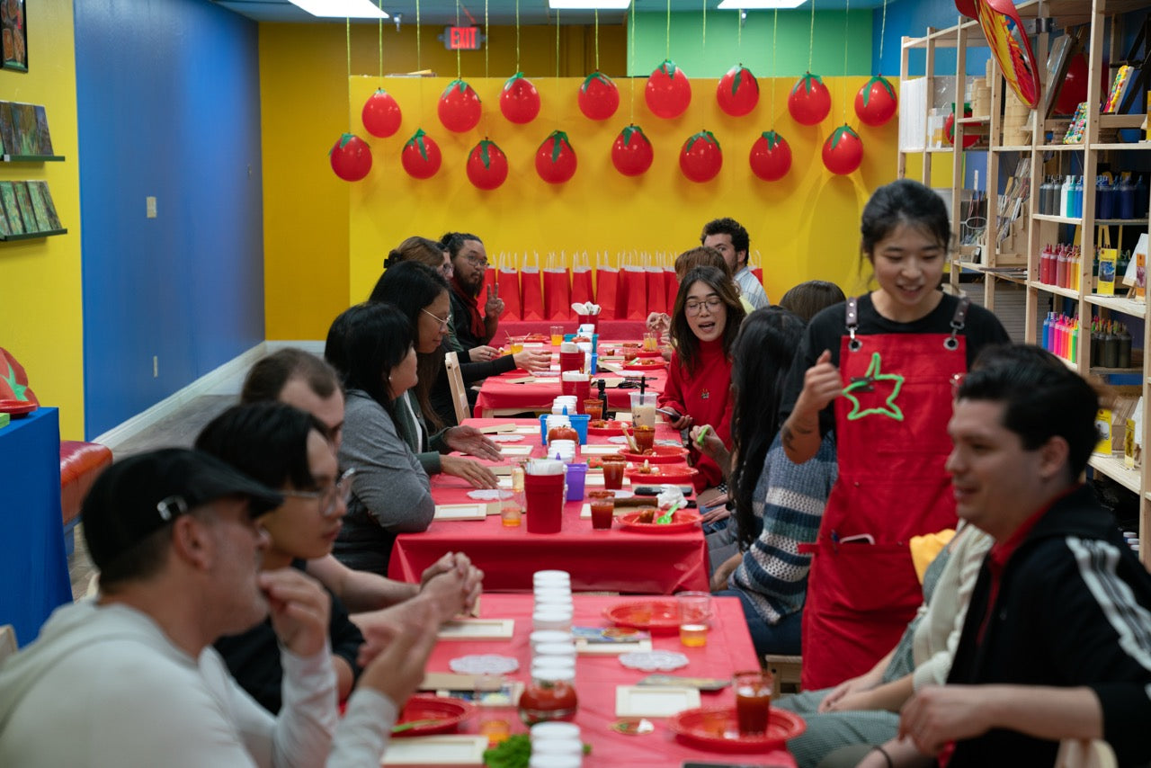 Group of people crafting together in a colorful room with red tableware and decorations.